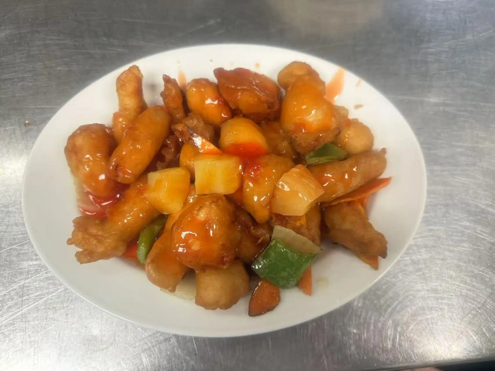 Sweet and Sour Chicken features fried chicken pieces coated in a sweet - and - sour sauce, mixed with vegetables like pineapple and green beans at China Panda, a Asian Cuisine restaurant in Athens